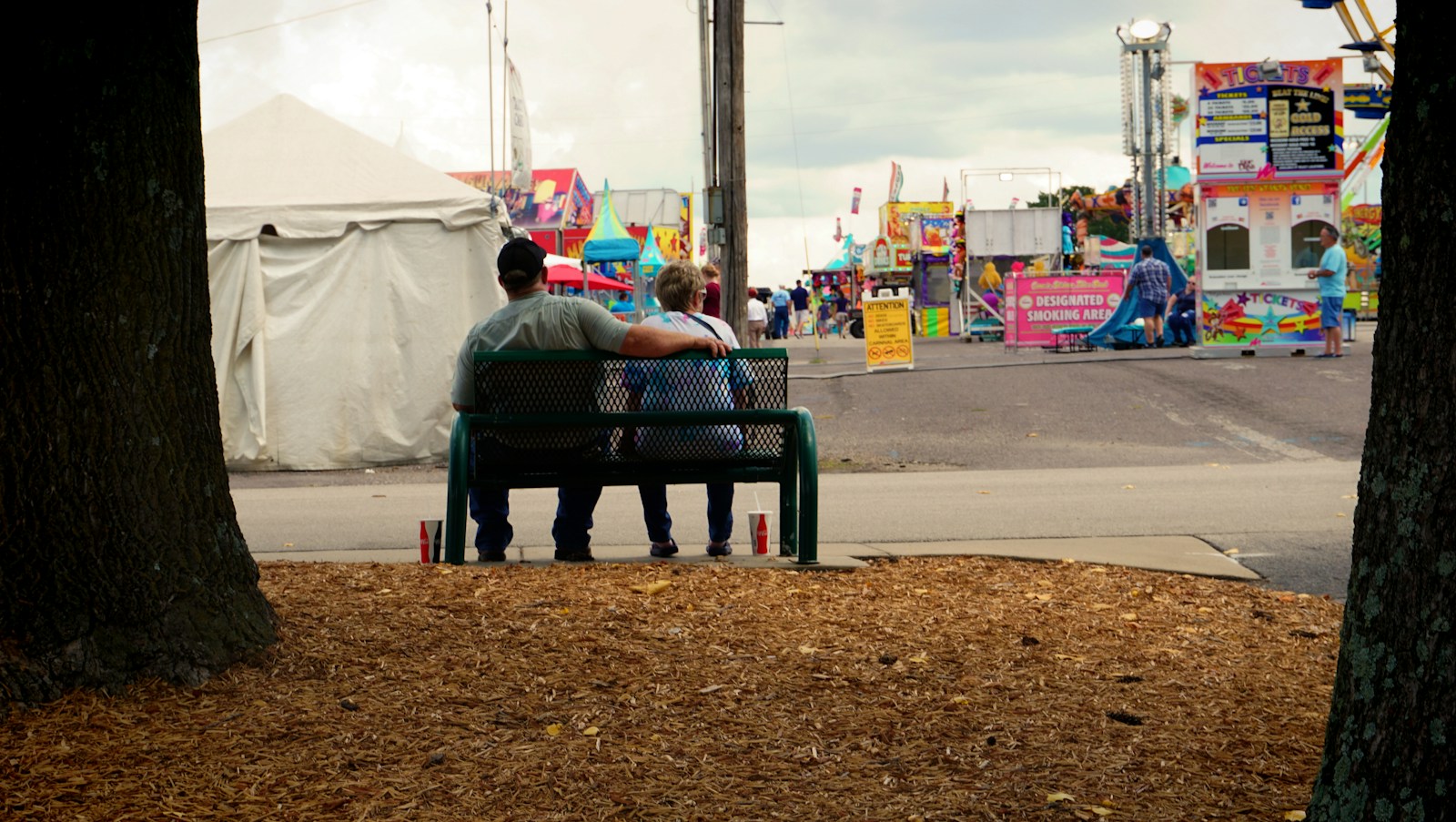 a man sitting on a bench in front of a carnival
